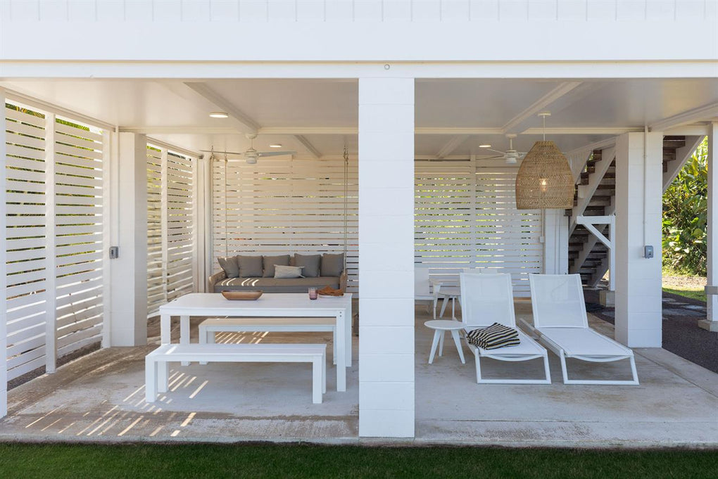 Outdoor patio area with white furniture and a view of the interior.